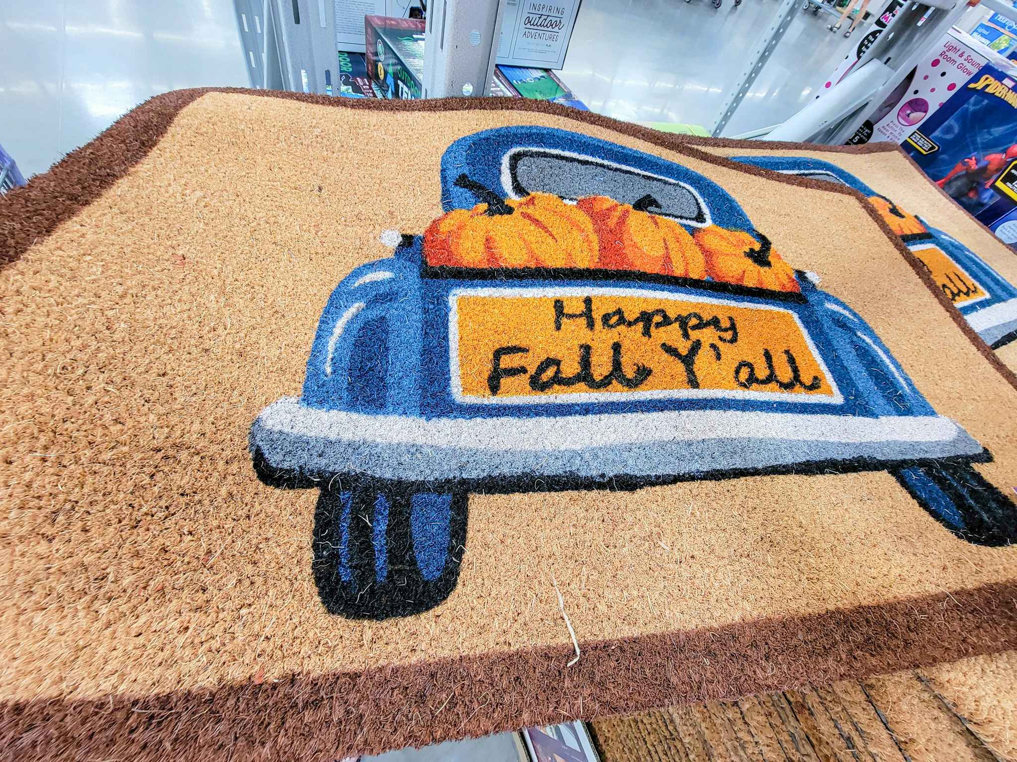 doormat with a blue truck on it that says happy fall y'all with pumpkins in it