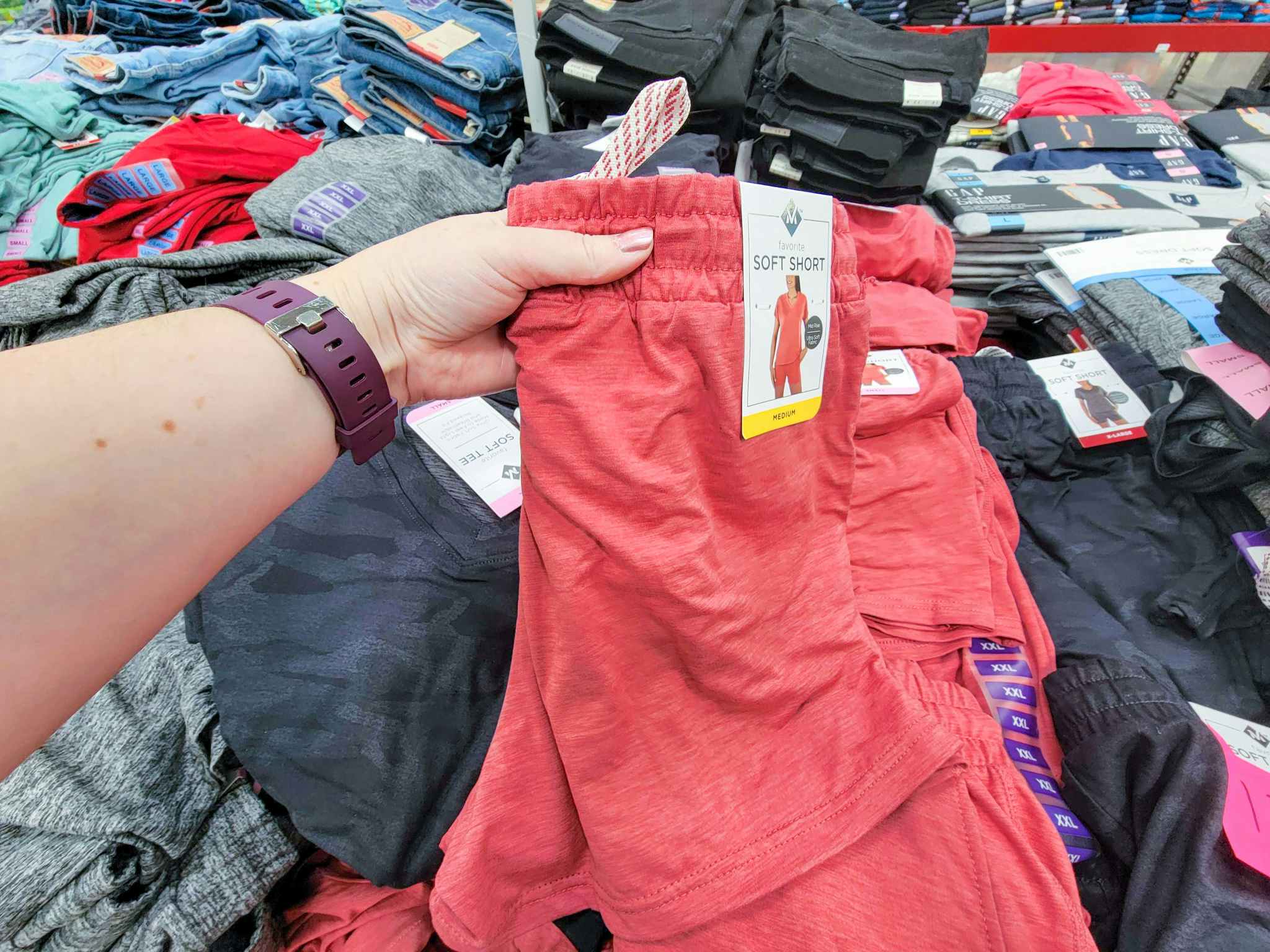 hand holding a pair of coral colored soft ladies shorts