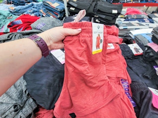 hand holding a pair of coral colored soft ladies shorts