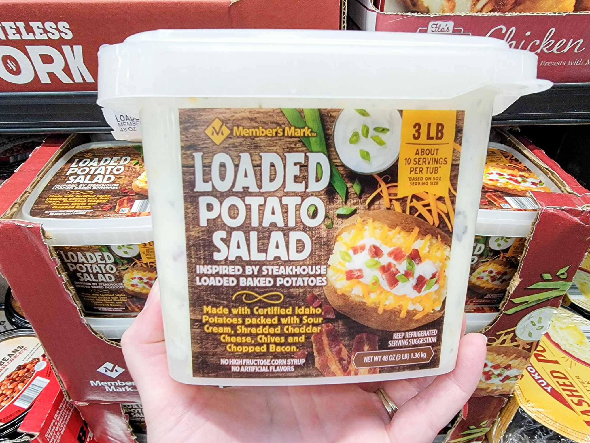 hand holding a tub of loaded potato salad