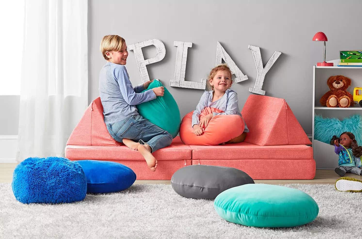 2 kids playing on a coral colored repositionable sofa for kids