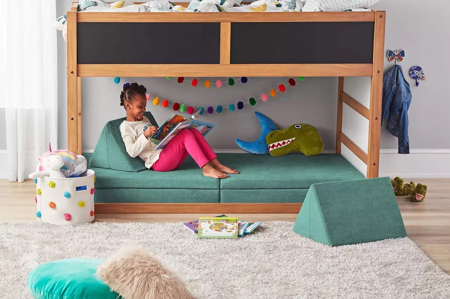 child sitting on a repositionable sofa for kids under a bunk bed