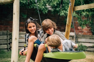 3 kids in a green gliding nest swing
