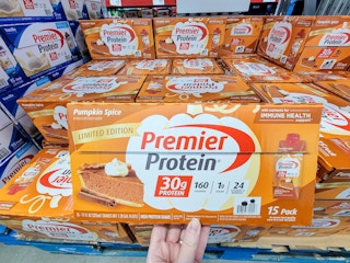 hand holding a box of 15 premier protein pumpkin spice flavored drinks