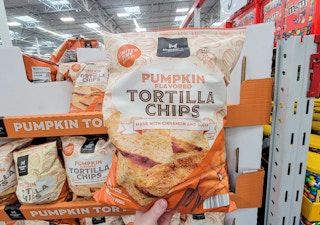 hand holding a bag of pumpkin flavored tortilla chips