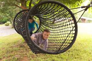 2 kids playing in a 6 foot long rope climbing tunnel connected to 2 trees