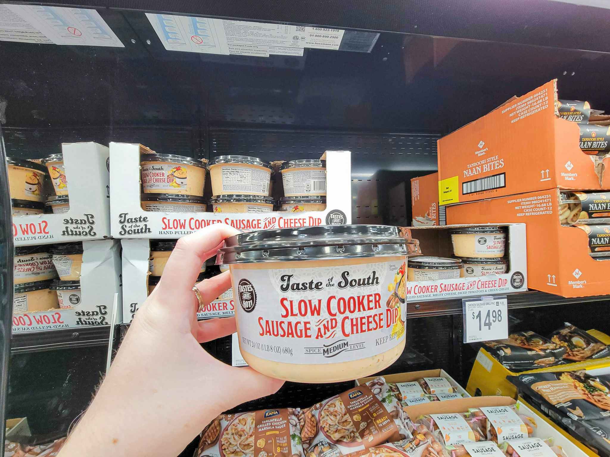 hand holding a container of sausage and cheese dip