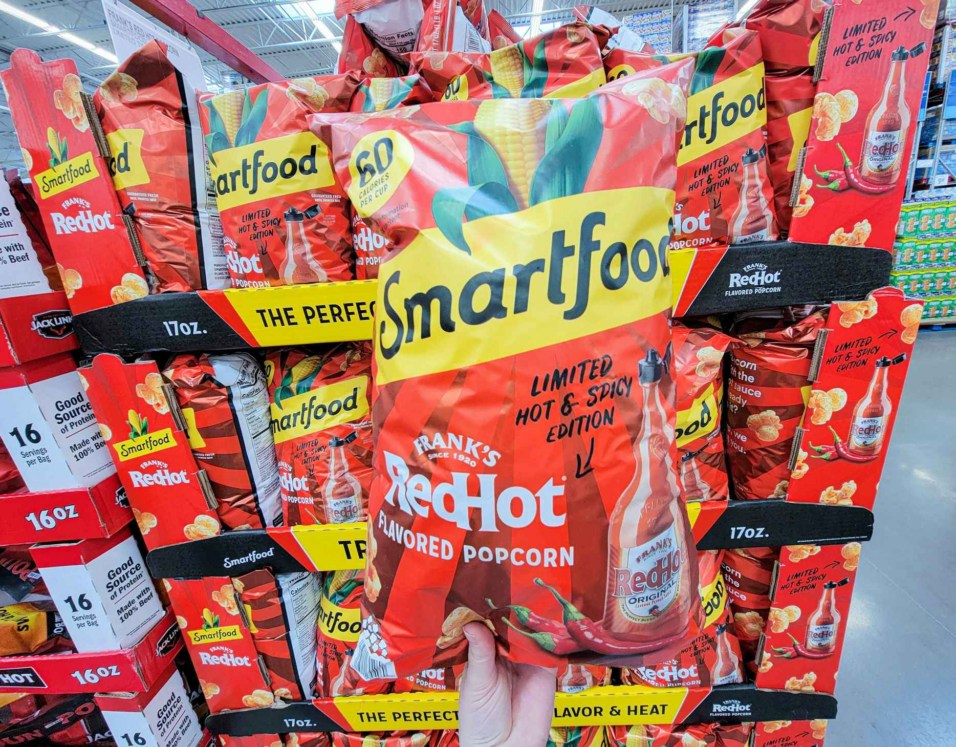 hand holding a bag of smartfood frank's red hot sauce flavored popcorn