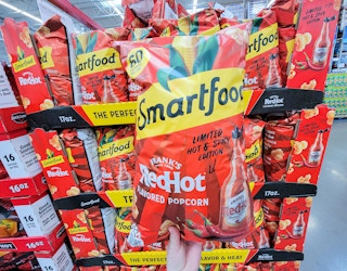 hand holding a bag of smartfood frank's red hot sauce flavored popcorn