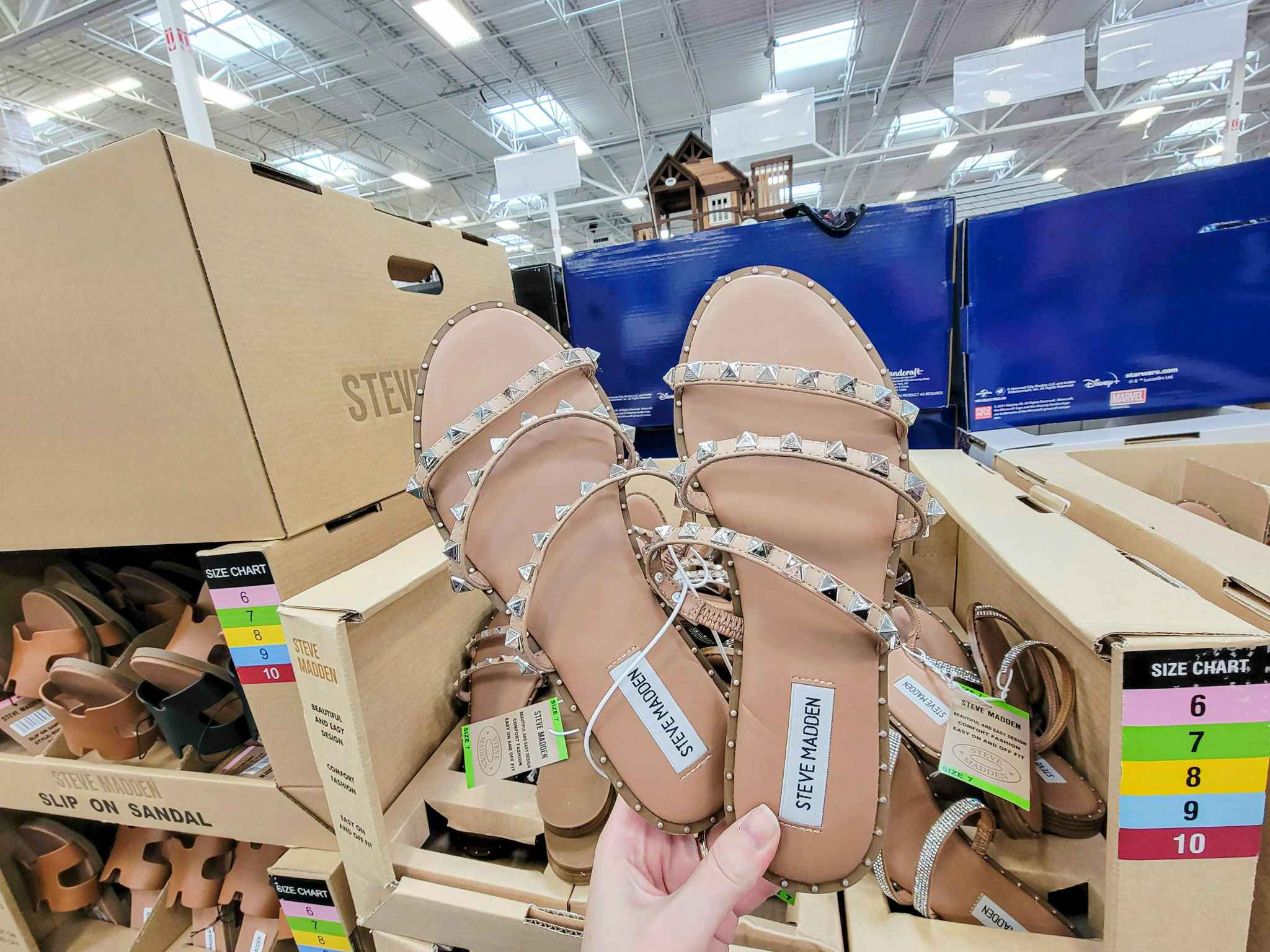 hand holding a pair of studded steve madden tan ladies sandals