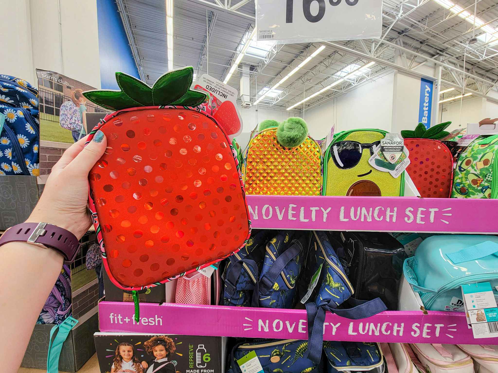 hand holding a strawberry lunch bag by a pineapple and avocado lunch bag