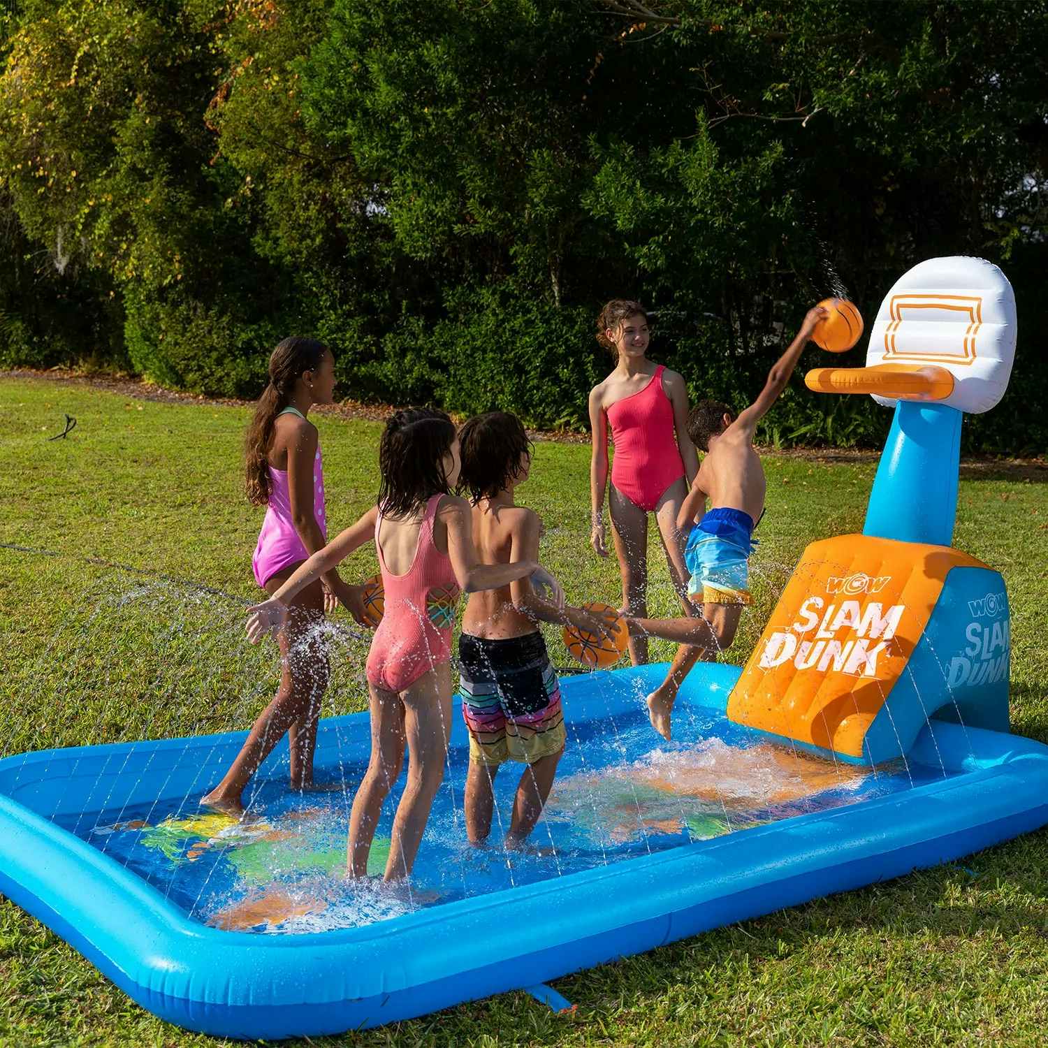 kids playing in an inflatable splash pad with a basketball hoop