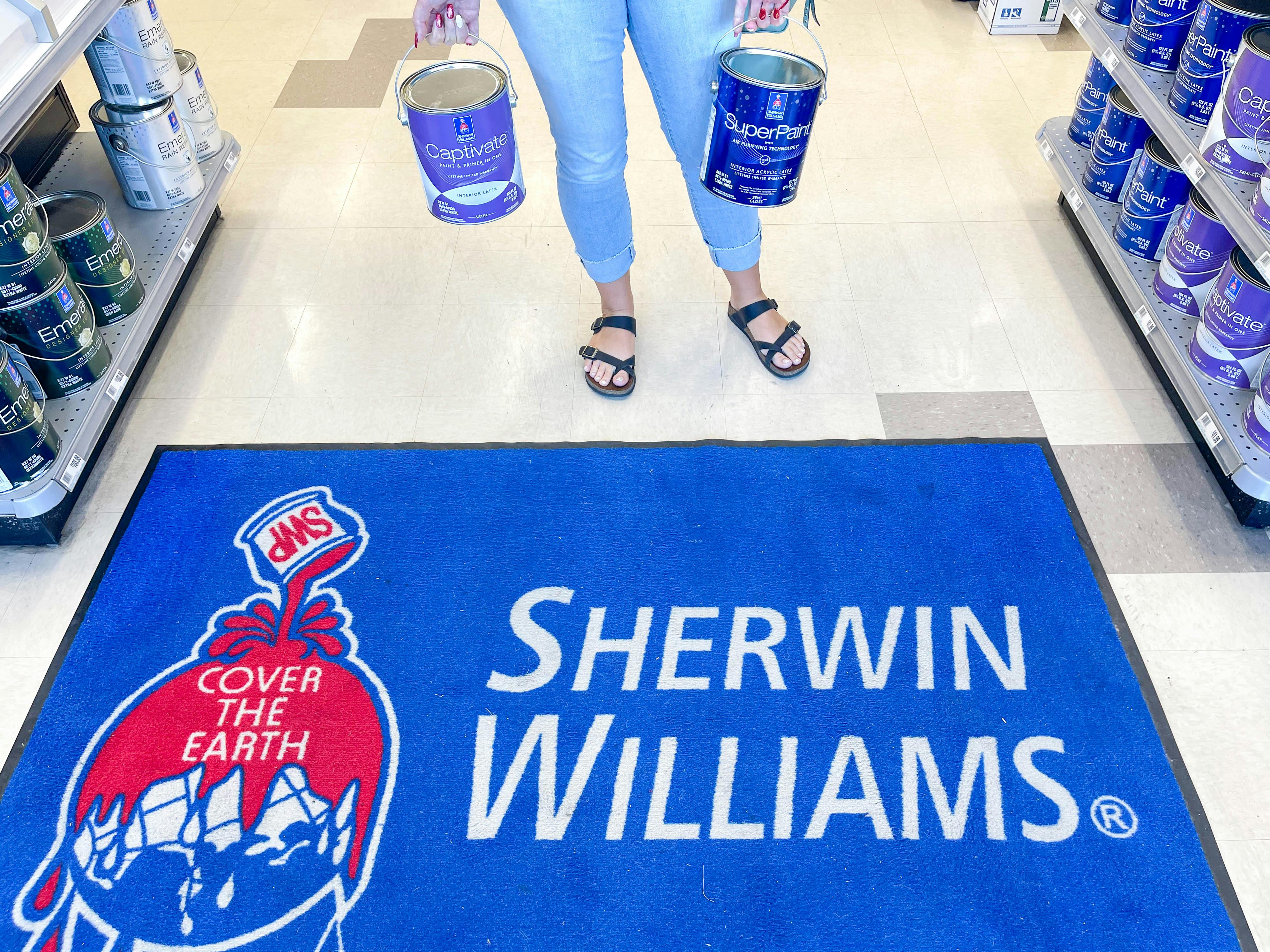 woman holding gallons of paint over a sherwin williams area rug
