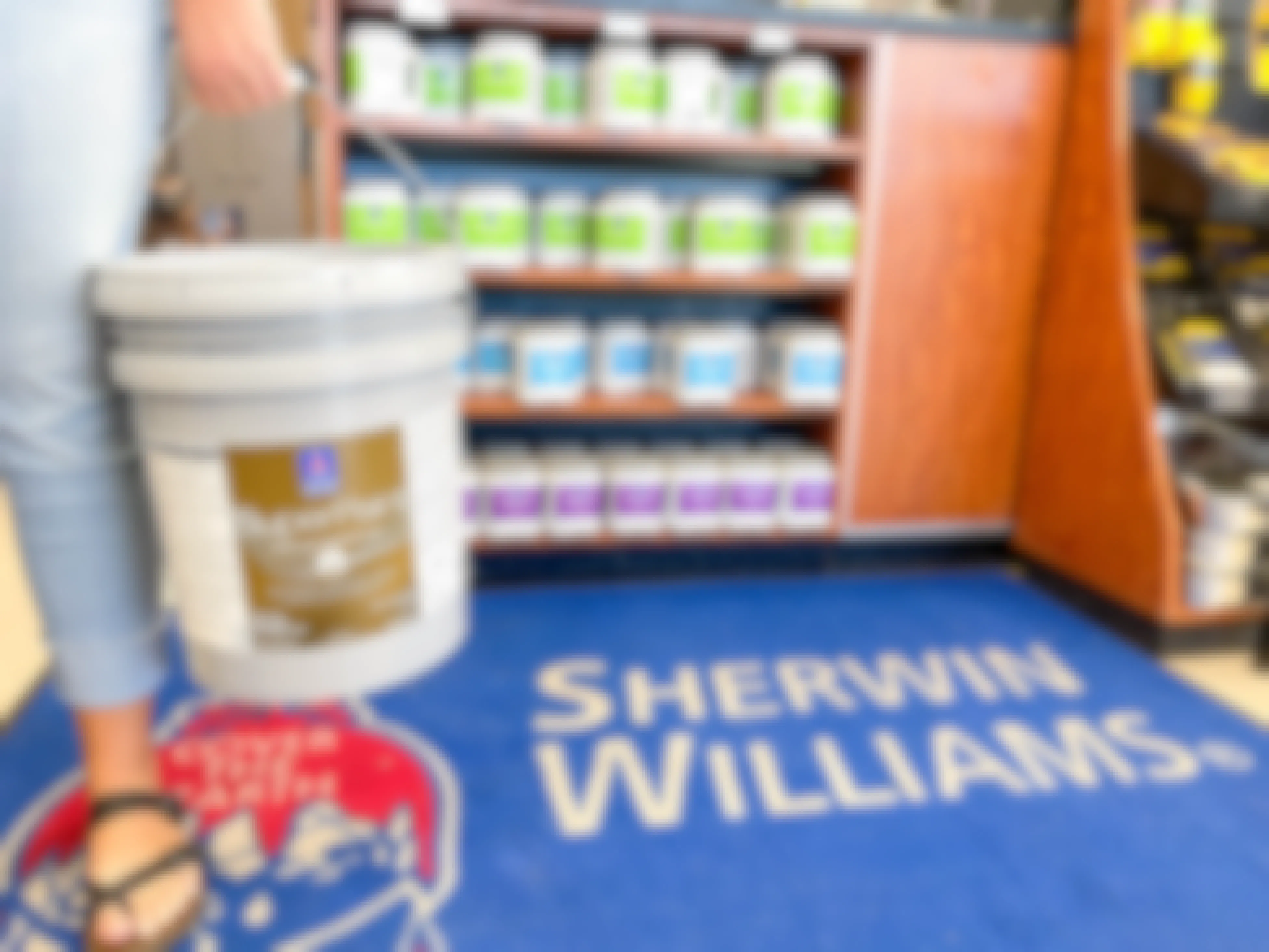 woman holding up a 5 gallon paint bucket in sherwin williams store 