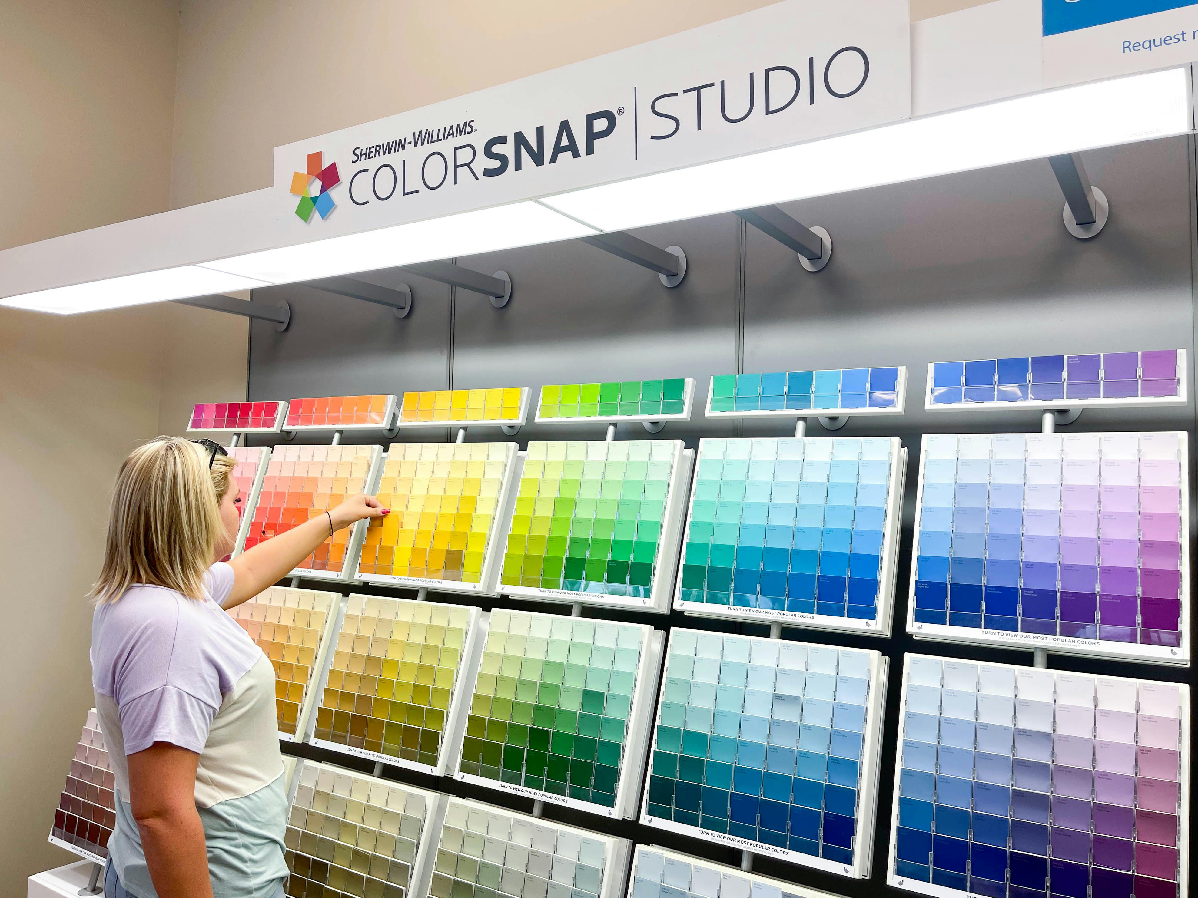 woman looking at a large wall of paint colors and swatches at Sherwin-Williams