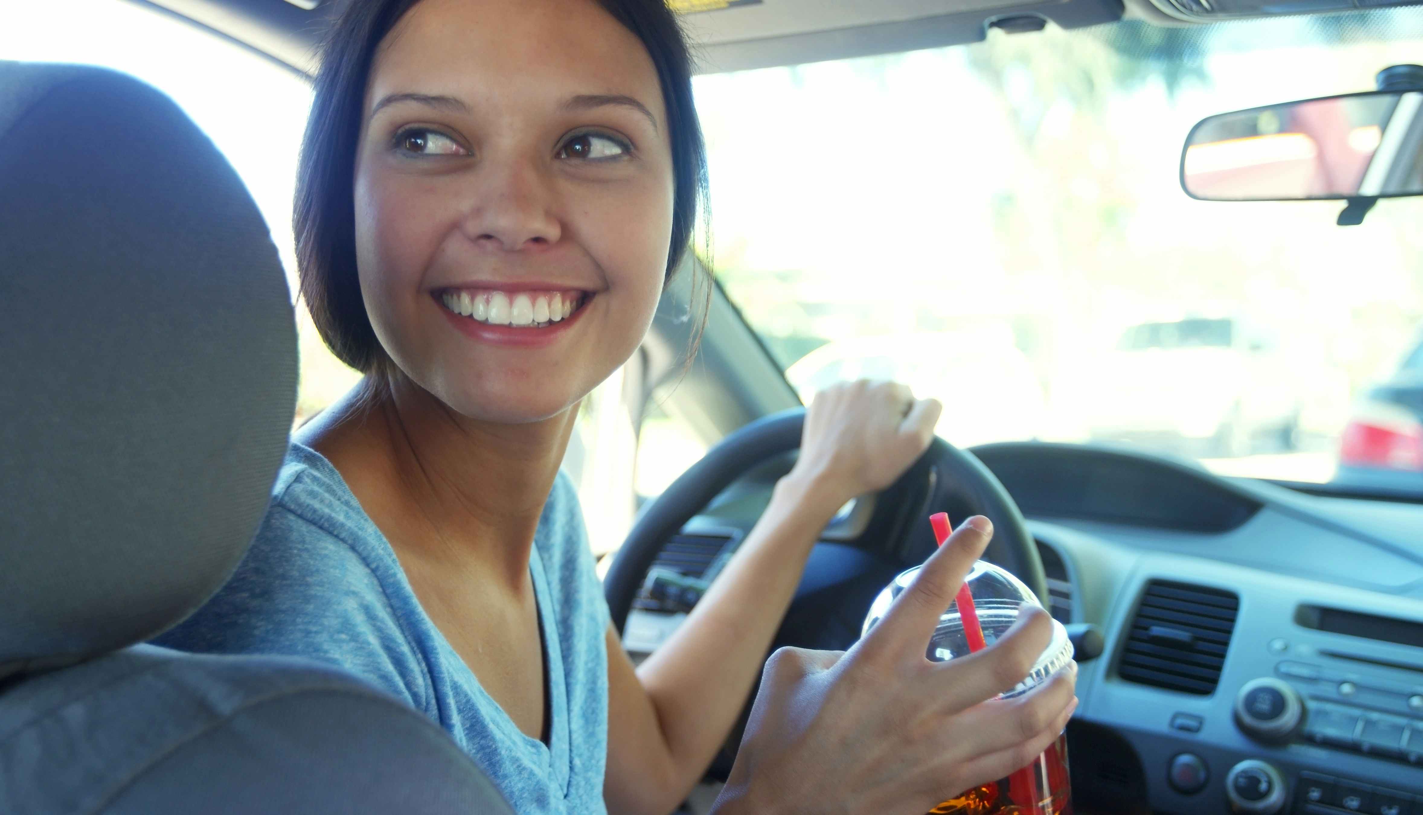 smiling woman driving a car and looking behind her