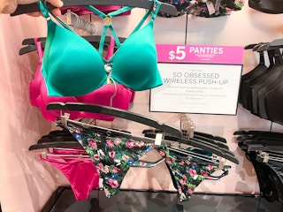 a green bra by a floral pair of panties by a sale sign