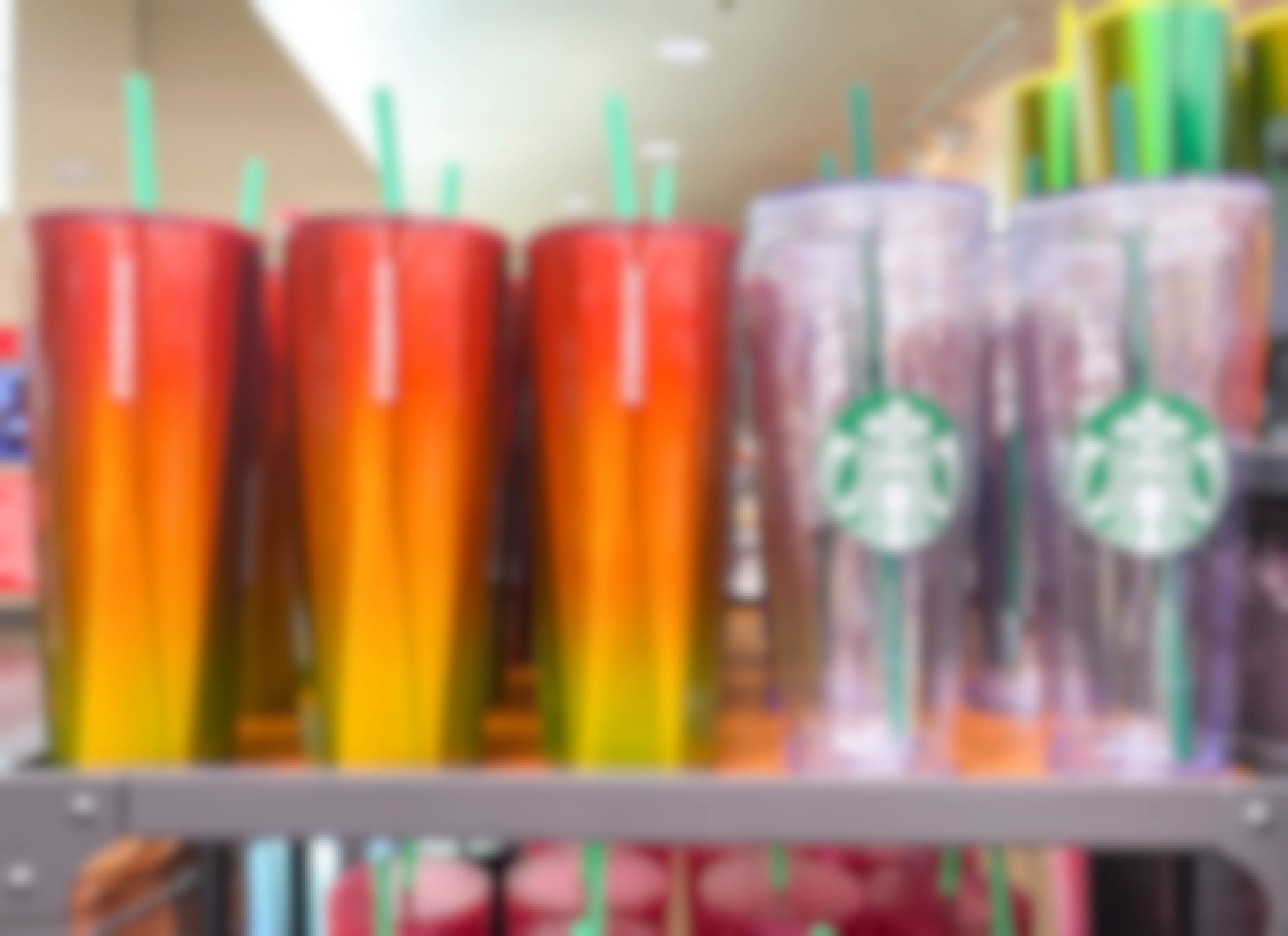 Starbucks reusable tumbler cups on a shelf inside a Starbucks cafe.