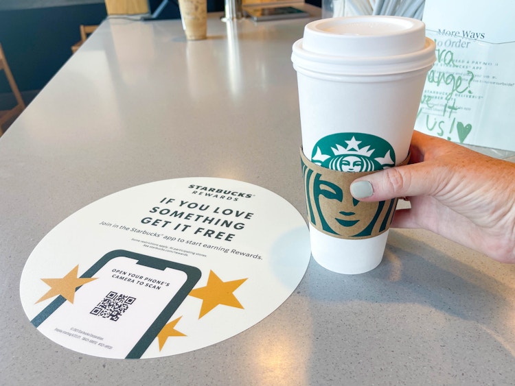 person holding a large starbucks hot beverage in store