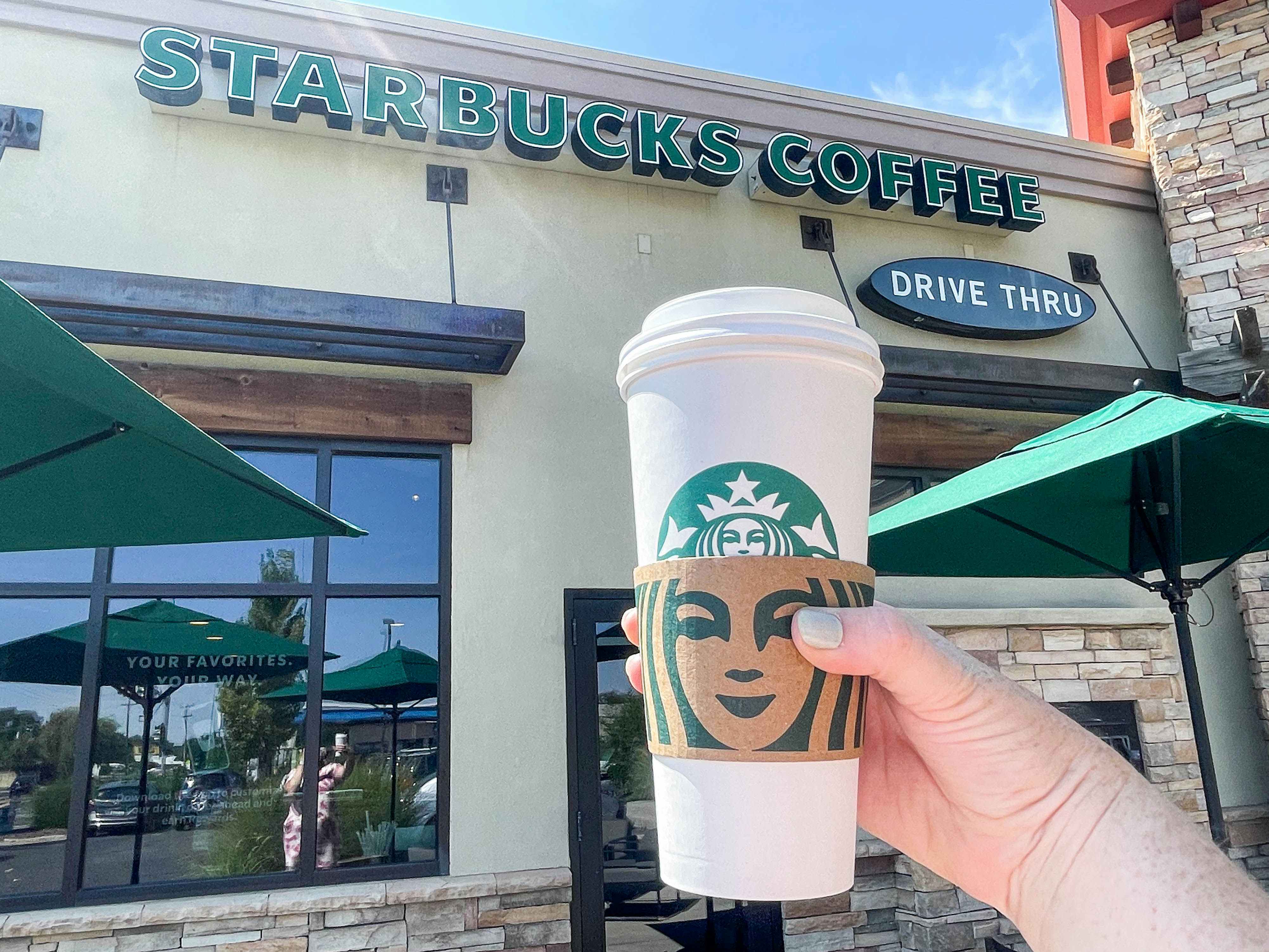 person holding a large starbucks hot beverage outside starbucks