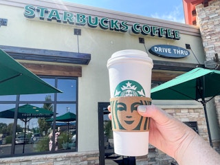 person holding a large starbucks hot beverage outside store