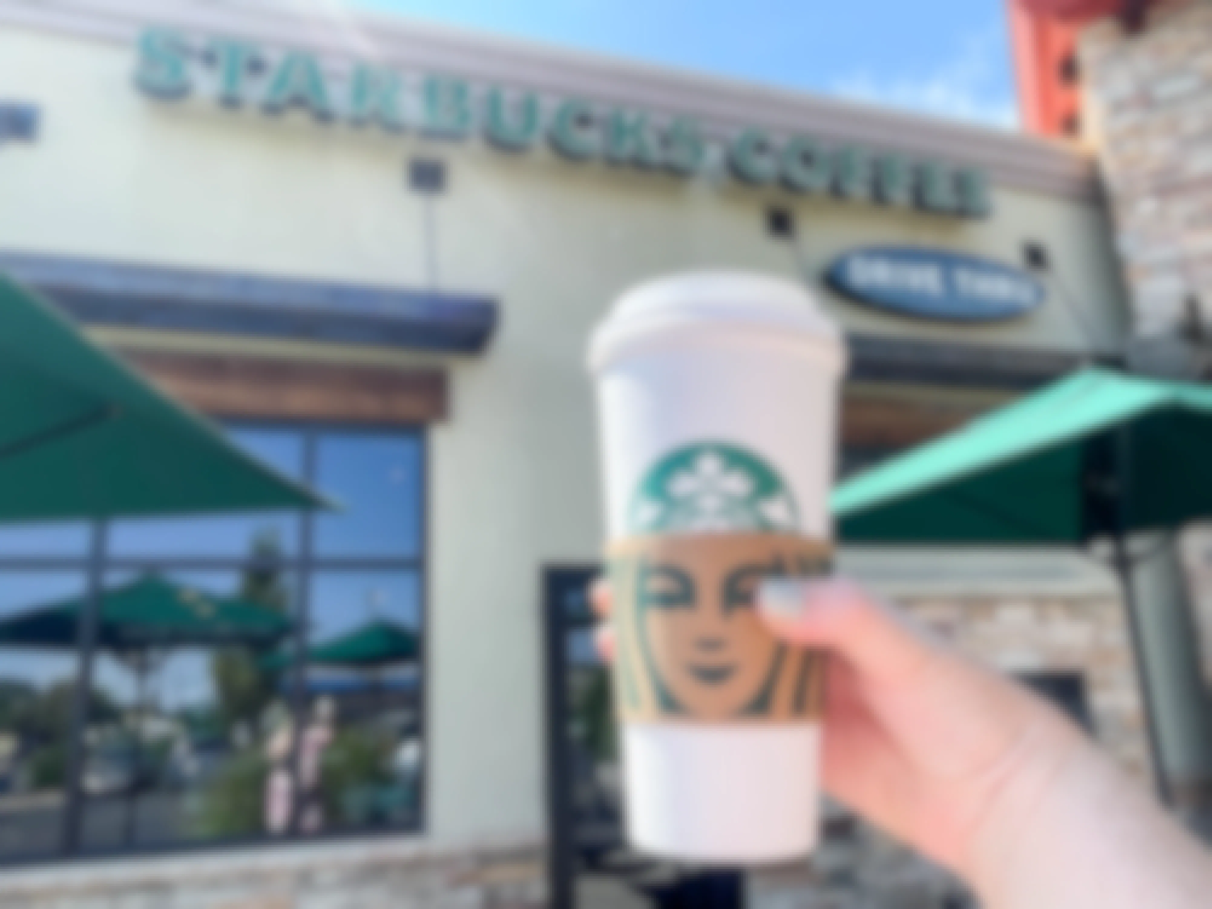 person holding a large starbucks hot beverage outside store