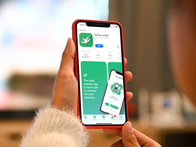 a woman looking at the survey junkie app in the app store on her iphone