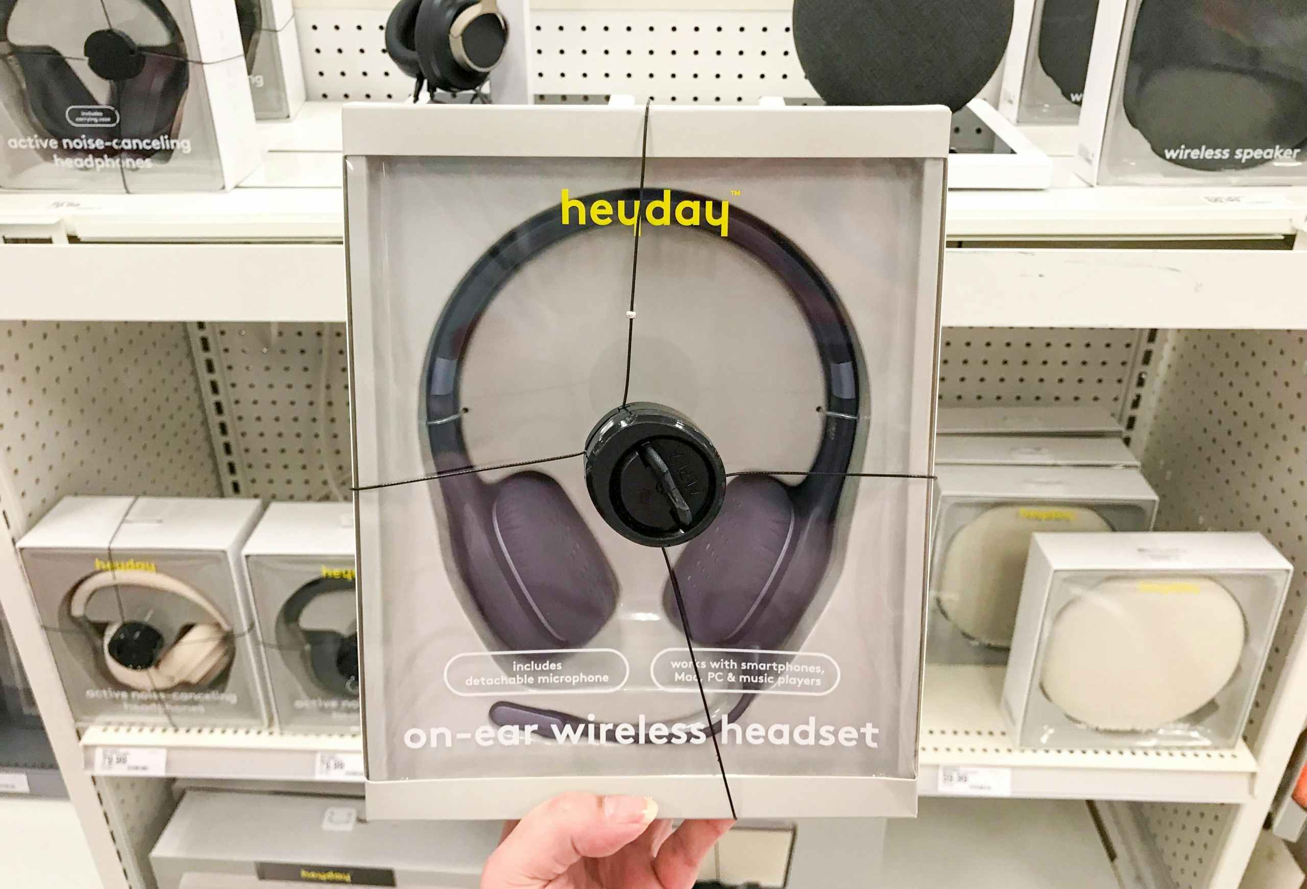 hand holding black Heyday wireless headphones in front of electronics shelf at Target