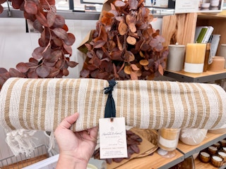 hand holding Hand and Hearth fall table runner in front of fall collection items