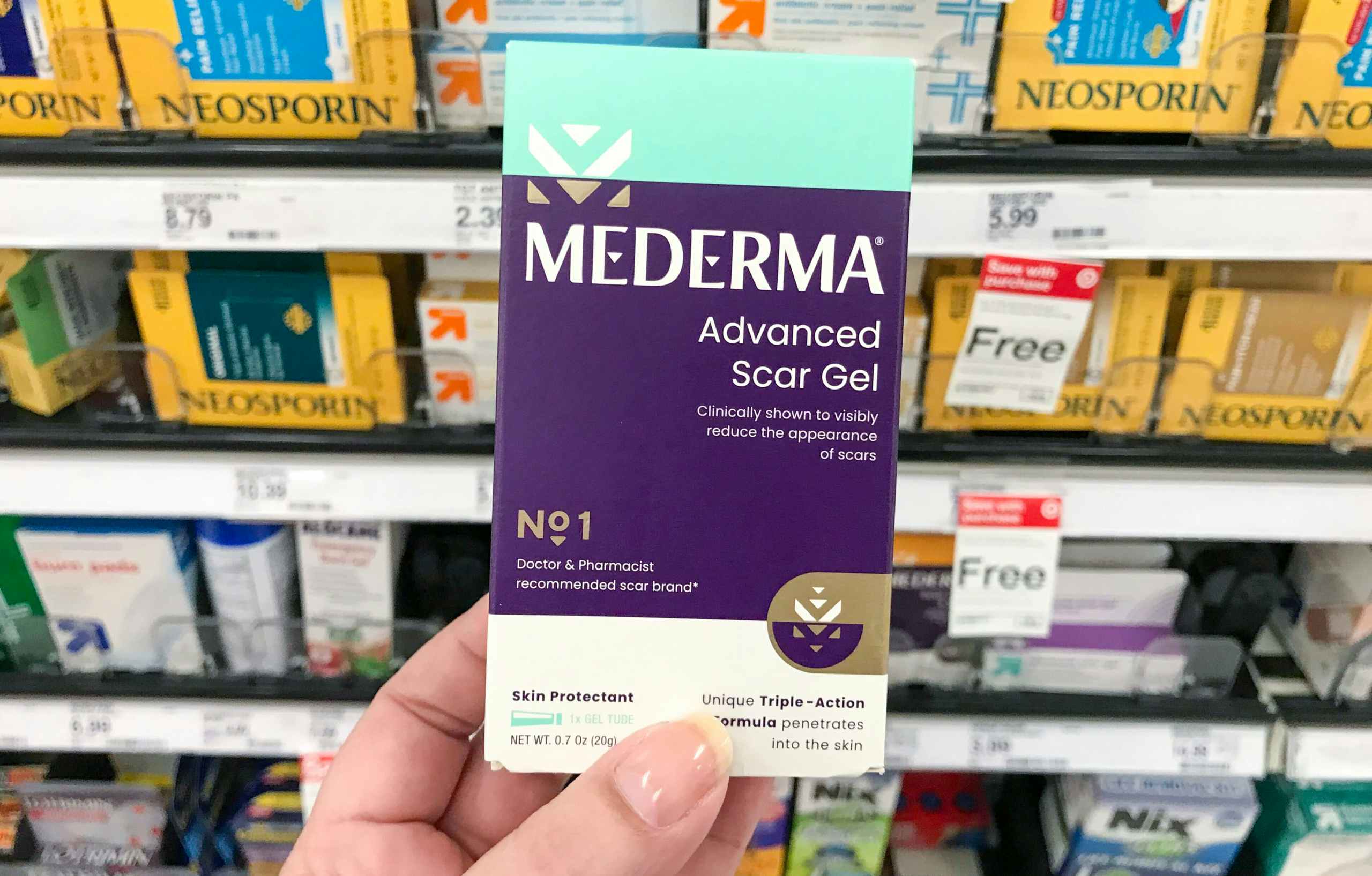 Mederma advanced scar gel with hand holding it in front of store shelf