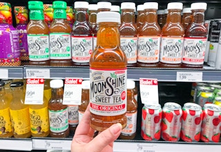 hand holding Moonshine SweetTea in front of refrigerated like items