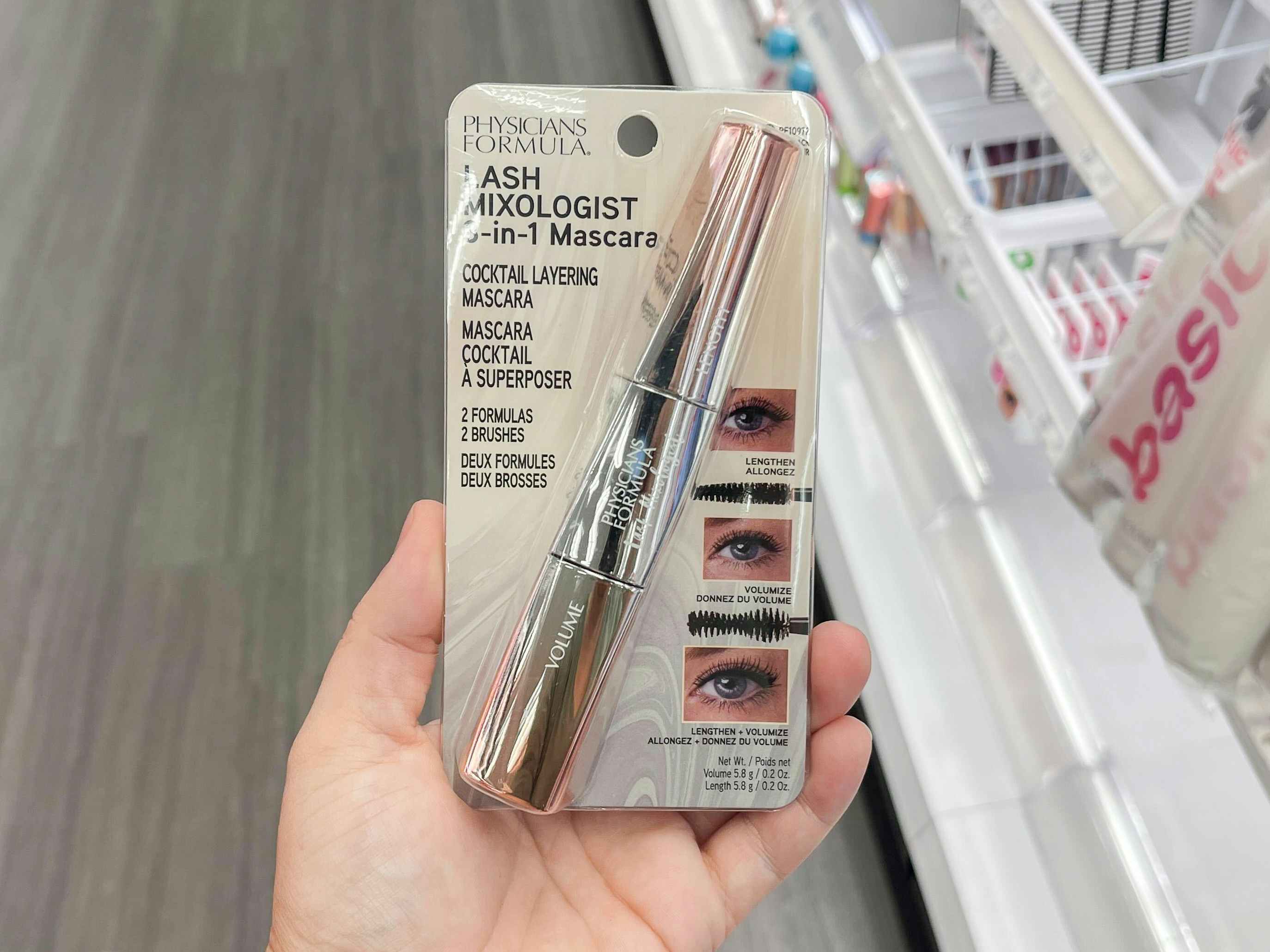 A person's hand holding a Physicians Formula Lash Mixologist Mascara in the beauty aisle at Target.