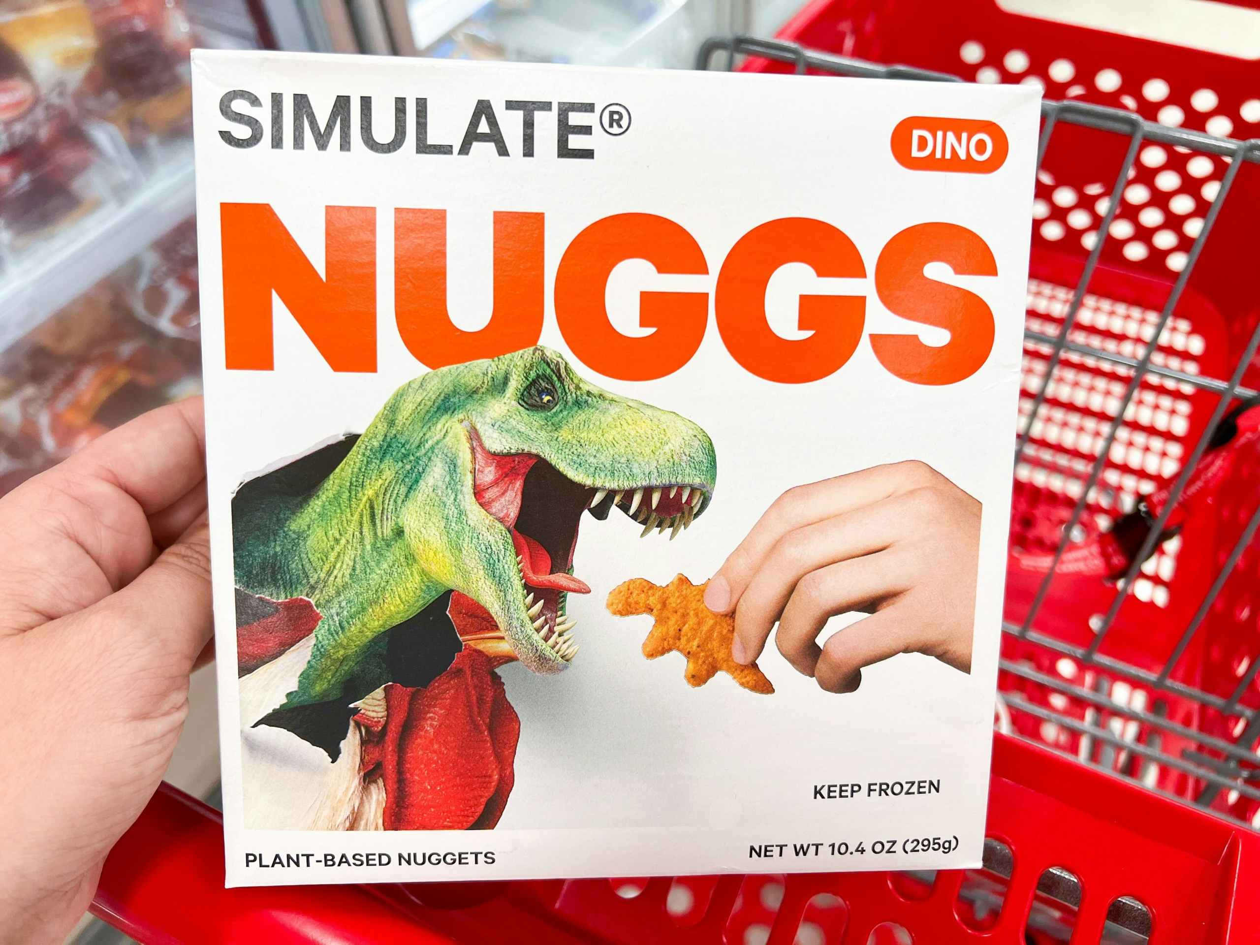 hand holding a box of Simulate Nuggs Dinos in a red Target cart