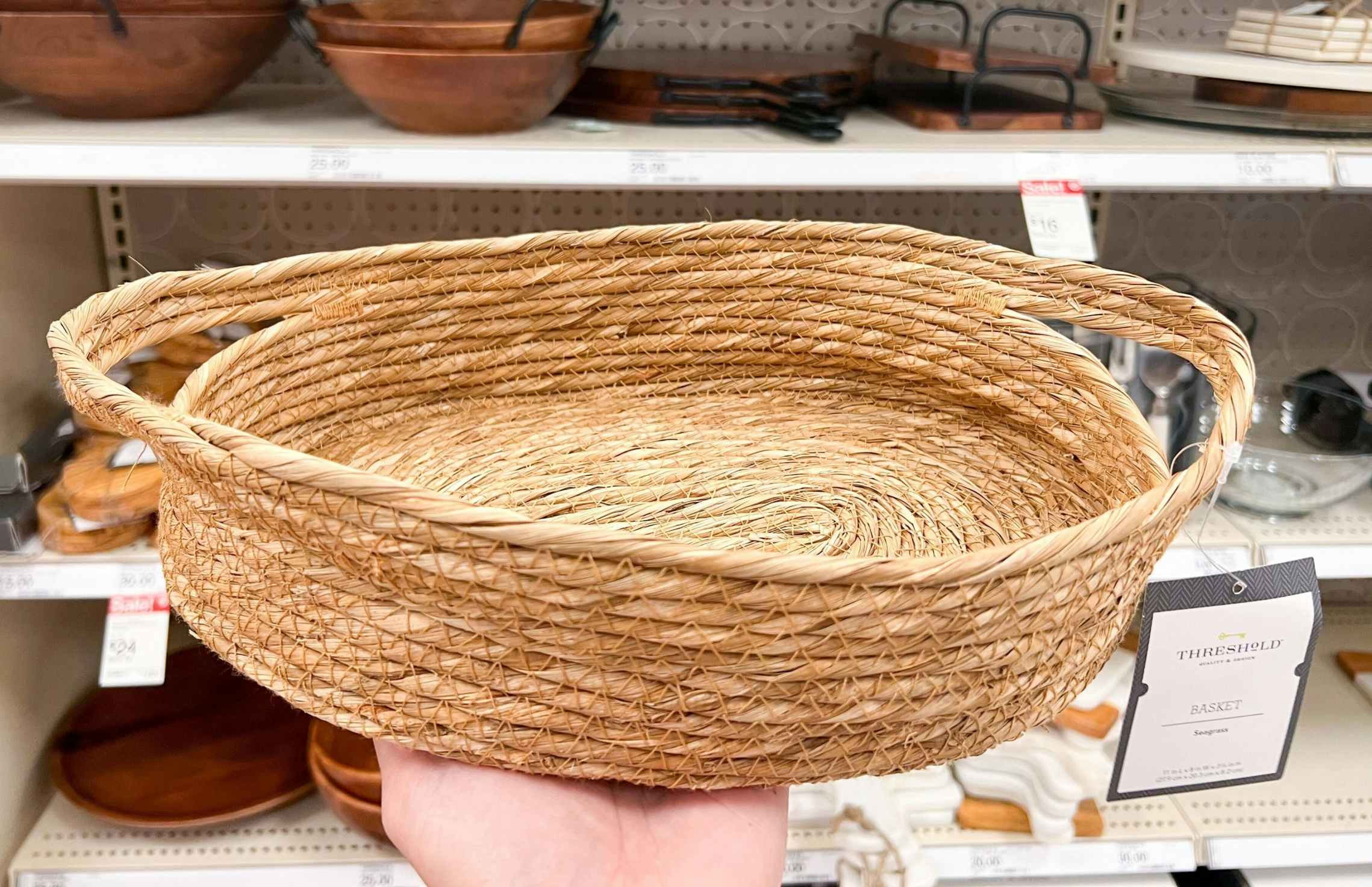 hand hold a Threshold seagrass basket in front of a Target shelf