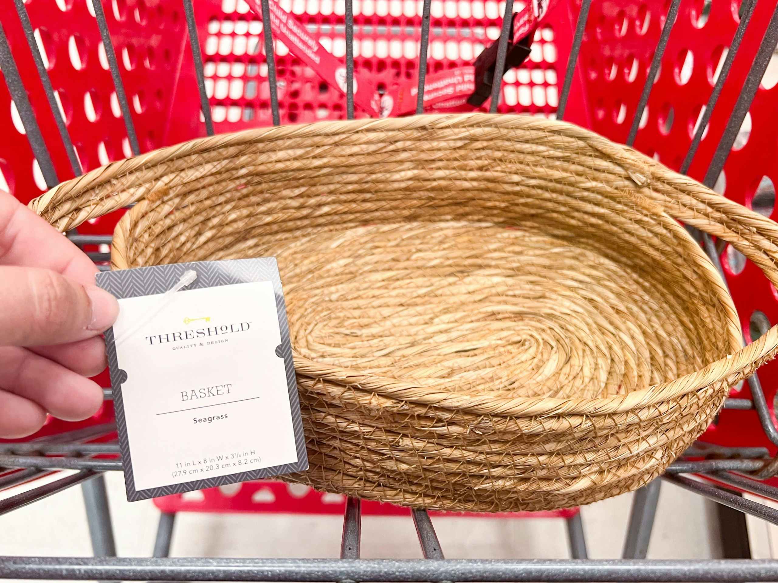 Threshold seagrass basket sitting in a cart with a hand holding the tag in front