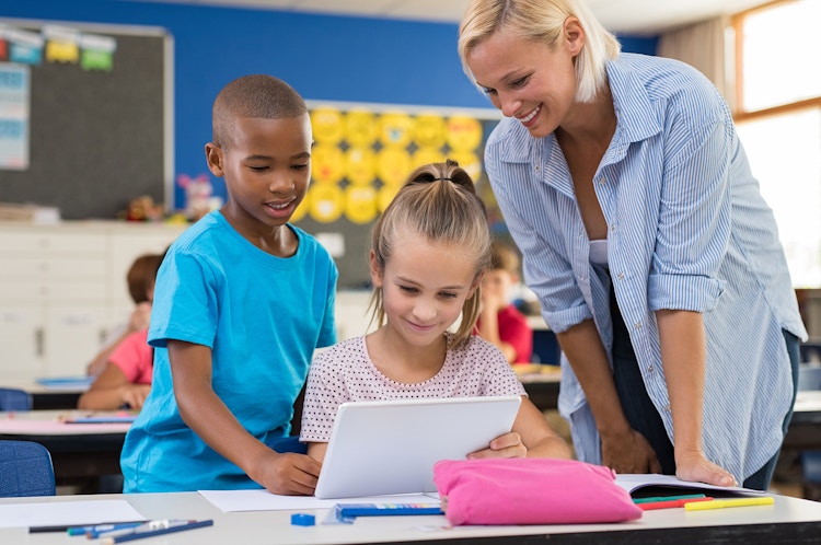 female teacher diverse students classroom tablet