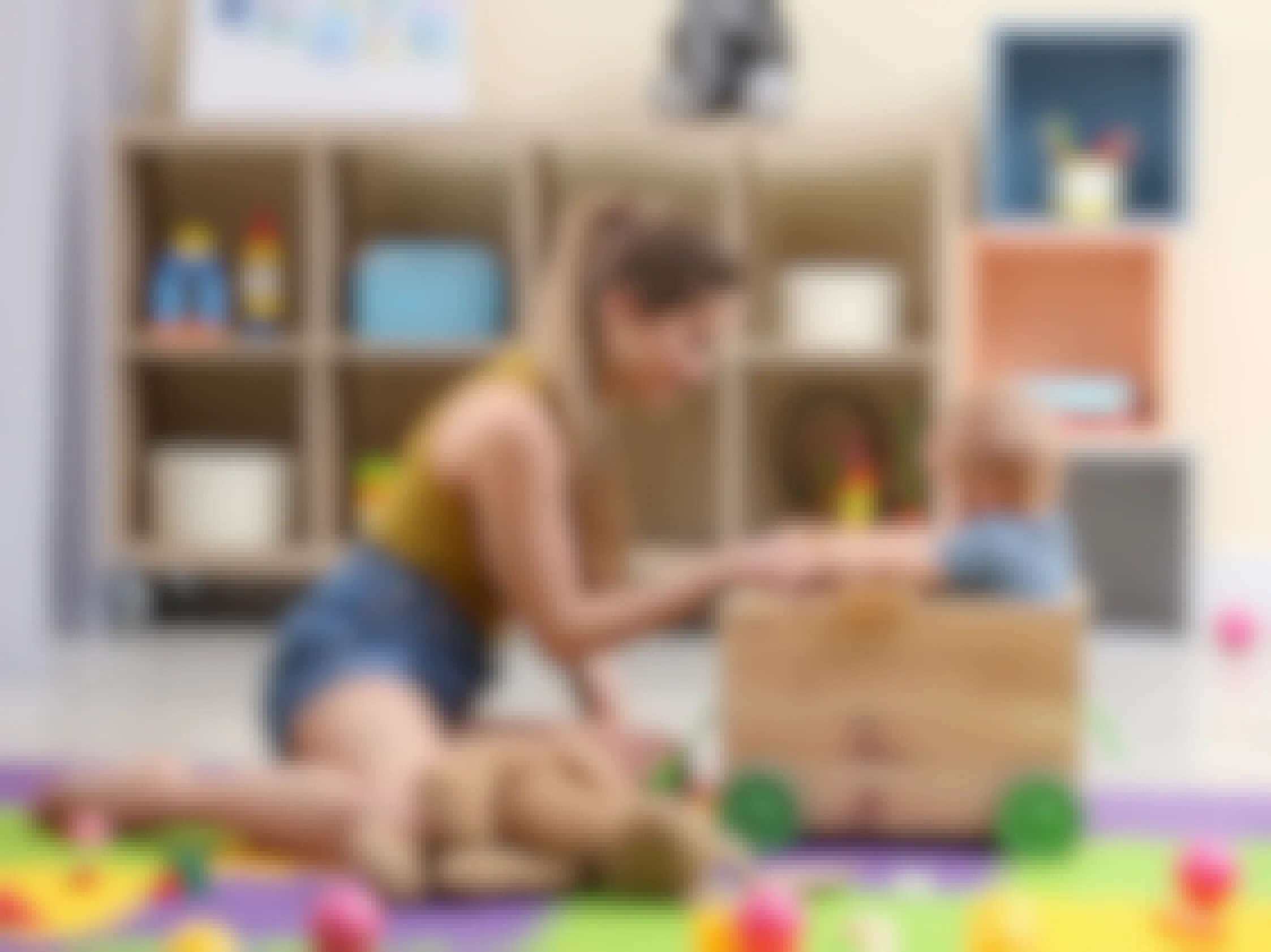 teenage girl babysitter playing with baby in playroom