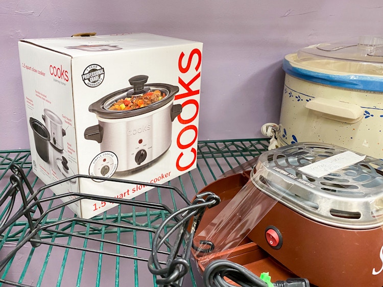 A Cooks slow cooker on a shelf in a thrift store.