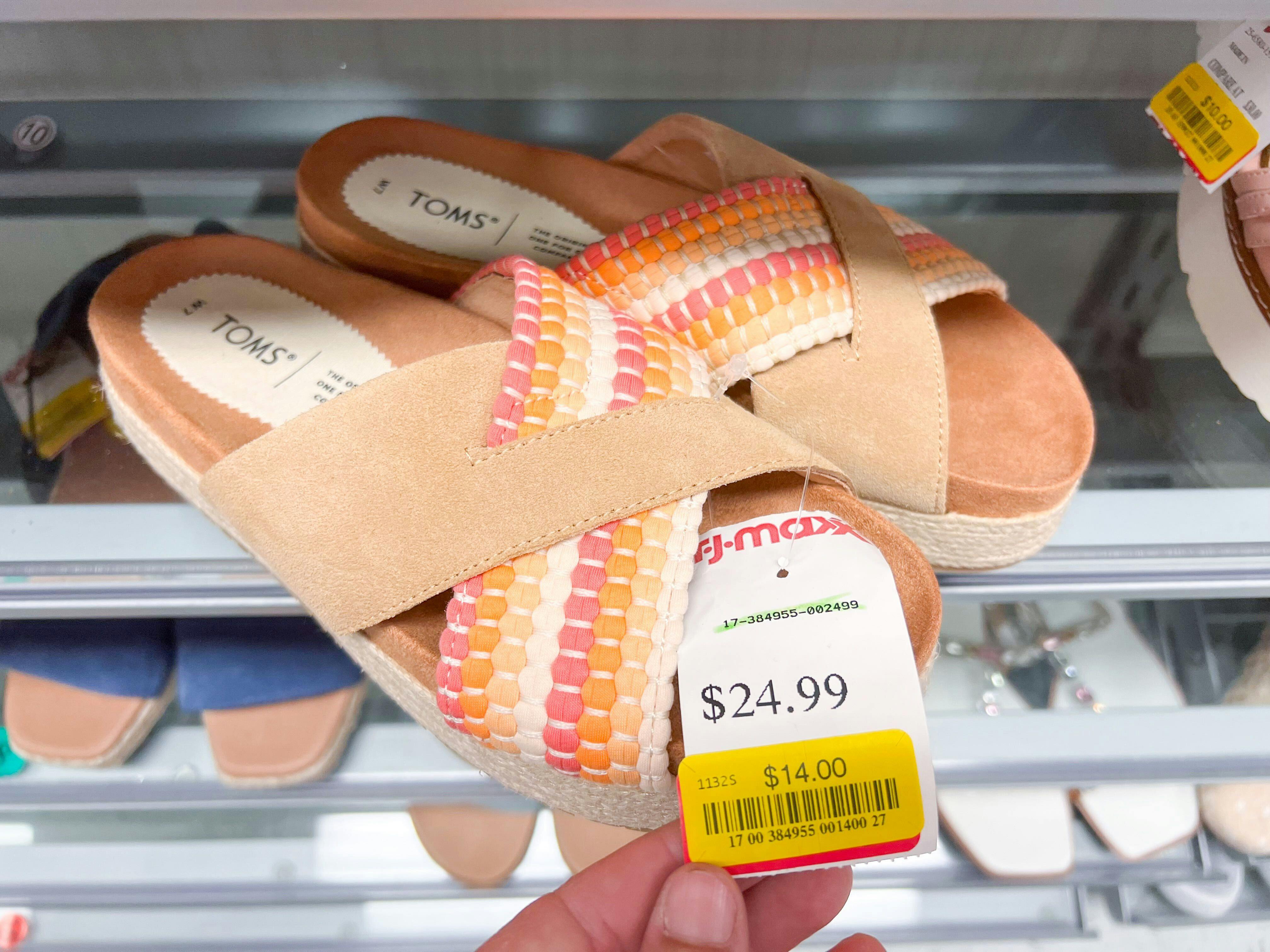 A pair of Toms sandals with a TJ Maxx clearance price tag for $14 on them.