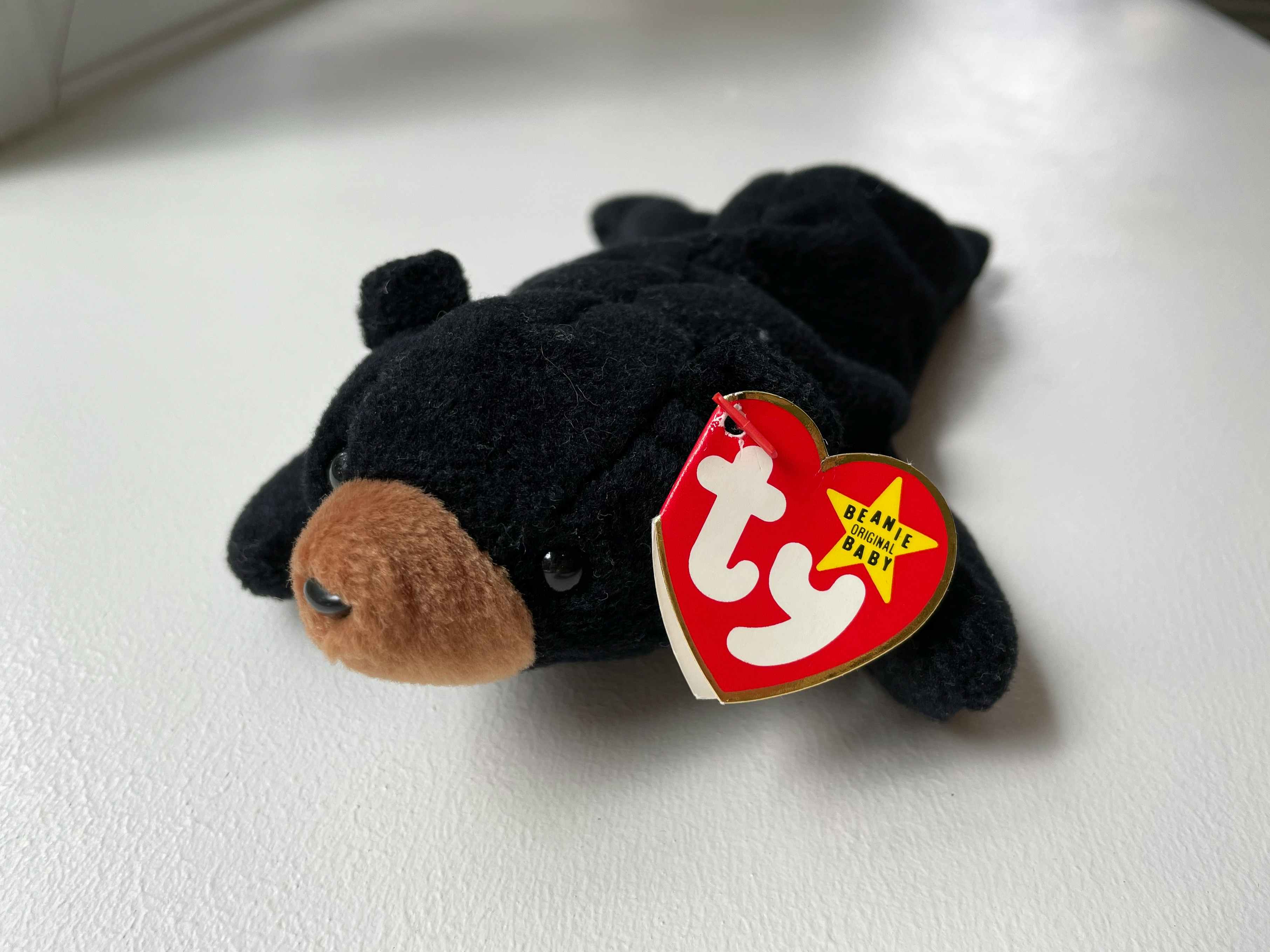 A Blackie the Black Bear beanie baby sitting on a white table.