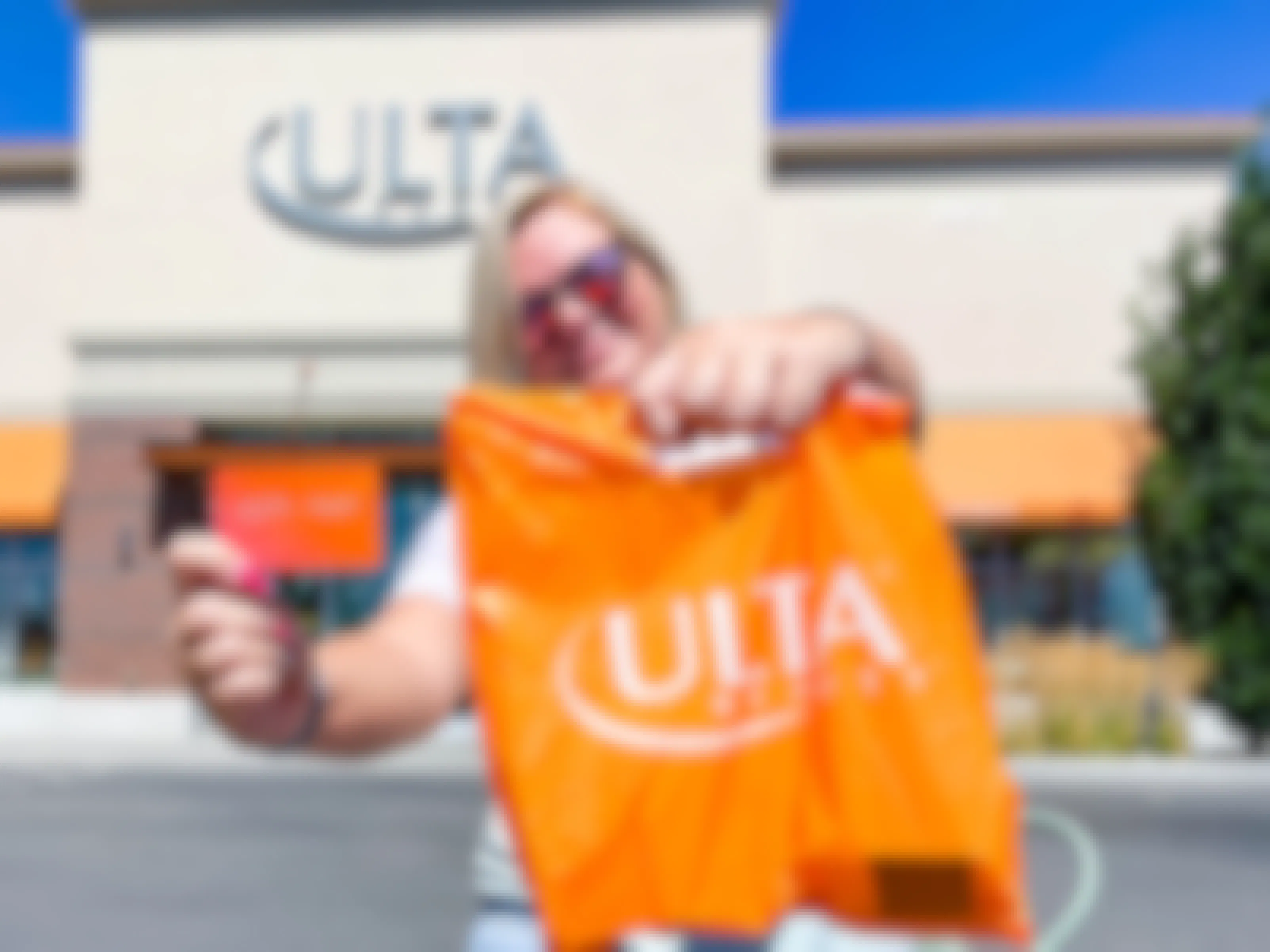 a woman holding a ulta bag and ulta credit card outside ulta