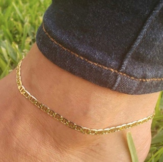 someone wearing an anklet with their foot in the grass