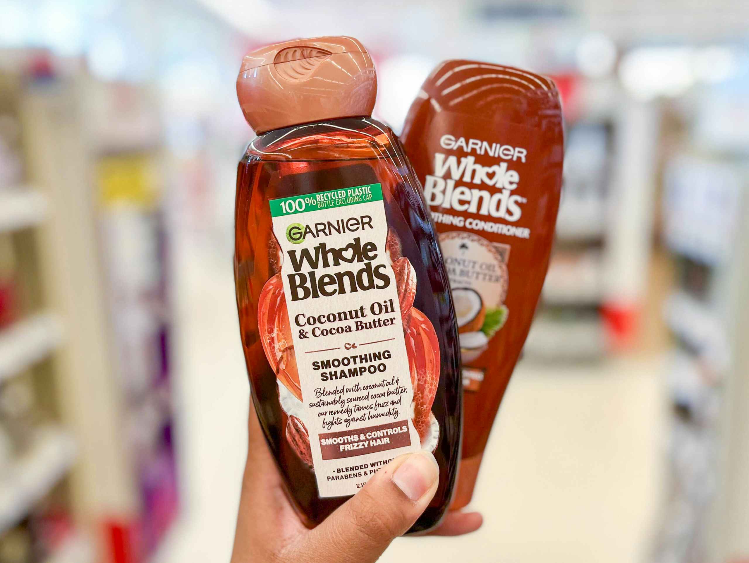 hand holding a bottle of Garnier Whole Blends shampoo and conditioner in aisle