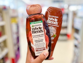 hand holding a bottle of Garnier Whole Blends shampoo and conditioner in aisle