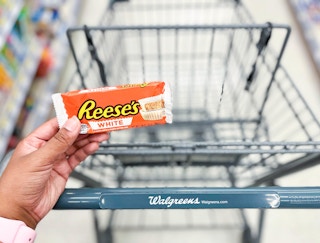 hand holding a pack of Reese's peanut butter cups in front of shopping cart