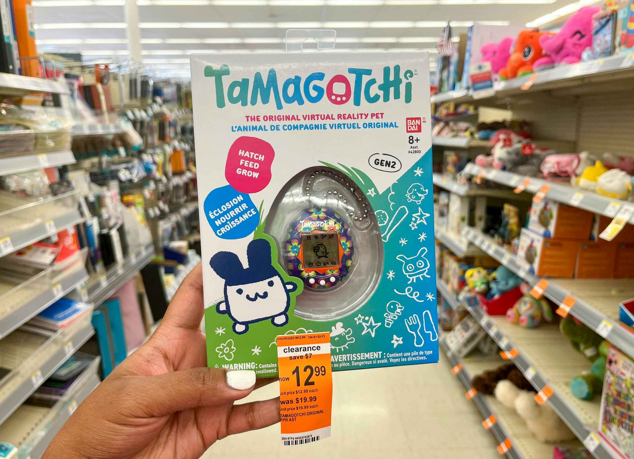 hand holding Tamagotchi in aisle with clearance tag attached