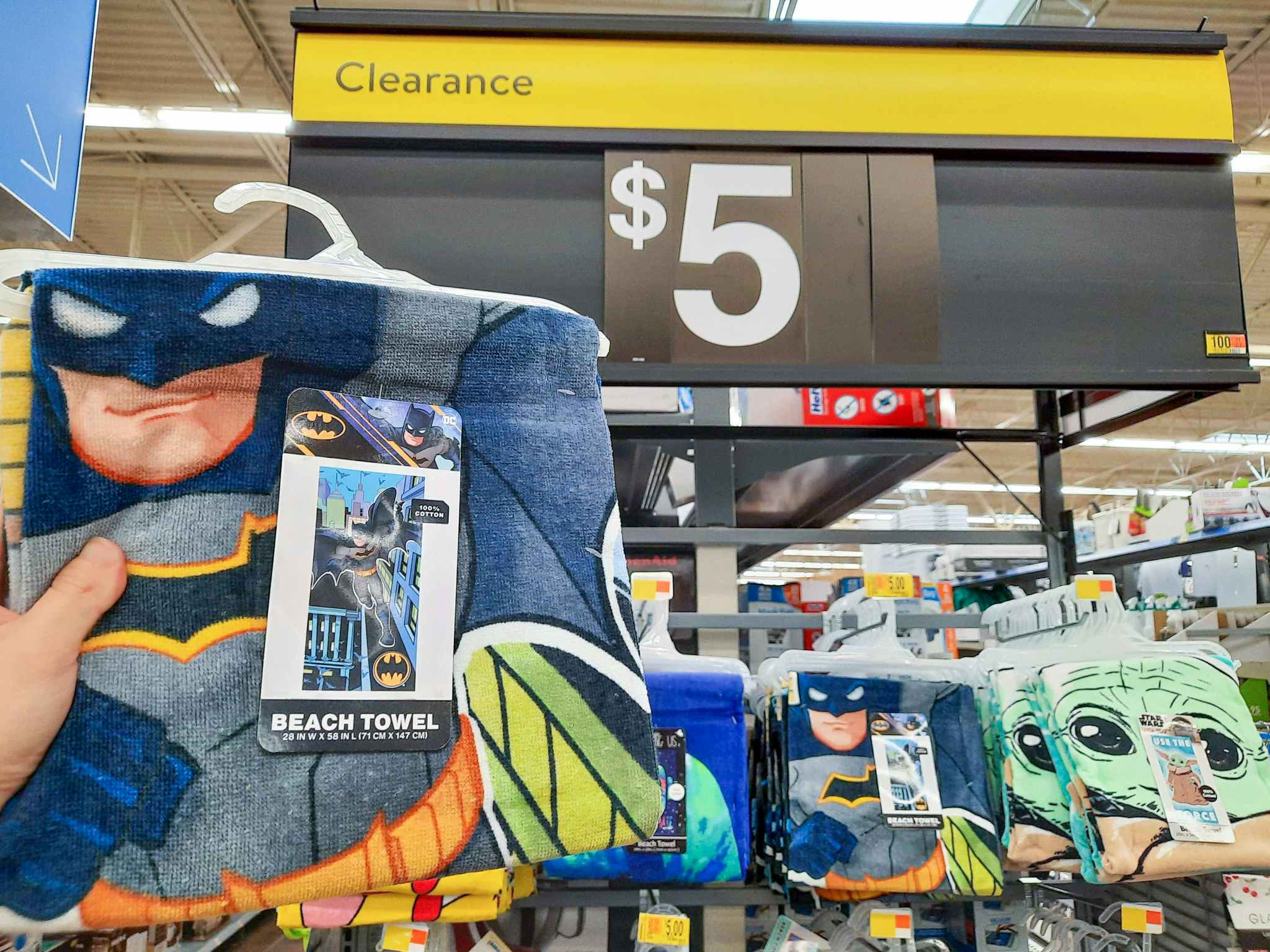 Batman Beach Towel held in front of $5 clearance sign.