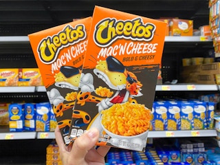 Two Cheetos Mac 'N Cheese products held in grocery section of Walmart