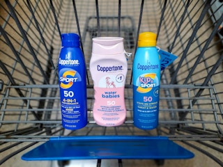 Three Coppertone Sunscreen products in Walmart shopping cart. Each product has a $2 hang tag coupon attached.