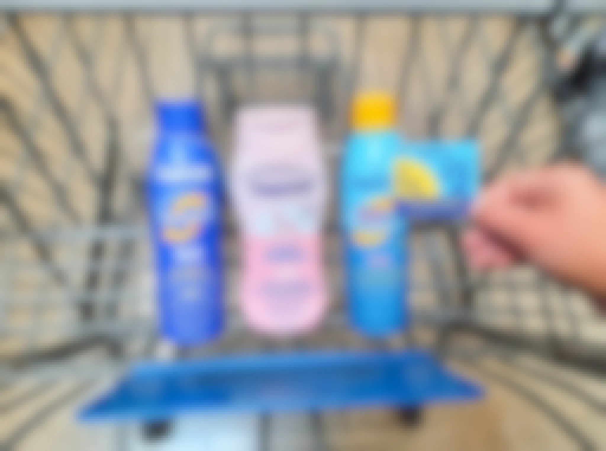 Coppertone Sunscreen products in Walmart shopping cart. Hand is holding a $2 coupon that is attached to one of the products.